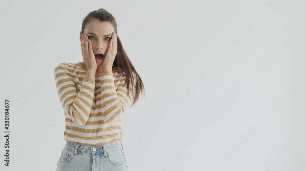 A beautiful excited shocked young woman is looking to the free space in the side over white background in studio A beautiful excited shocked young woman is looking to the free space in the side over white background in studio