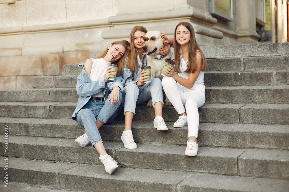 Beautiful girls drinking a coffee. Women in a spring city. Ladies with cute dog.