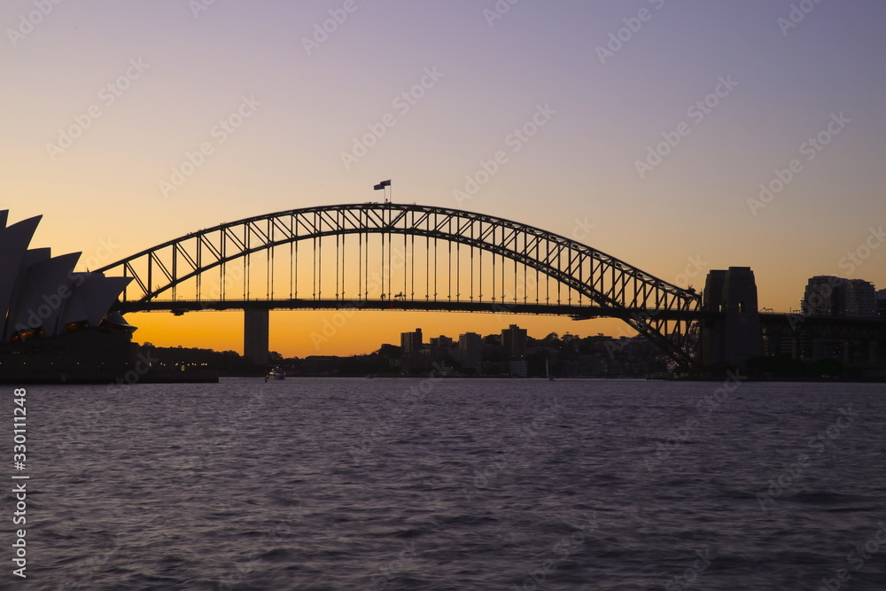 Panorama View of Sydney Harbour bridge opera house on a warm summer afternoon blue and orange skies illuminating Sydney Harbour Bridge
