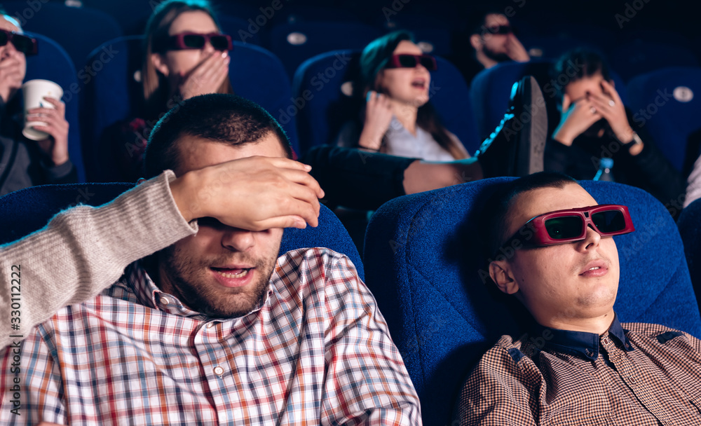 Spectators in a movie theater are sitting and watching a movie in 3D ...