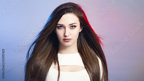 Photos portrait of confident beautiful girl with long hair on studio background, young