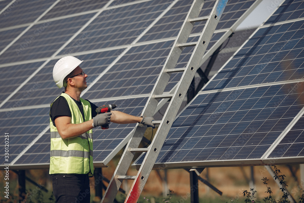 Engineer in a white helmet. Man near solar panel. Worker with a ladder Engineer in a white helmet. Man near solar panel. Worker with a ladder