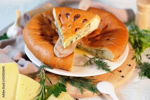 Round closed homemade baked pie with cheese and parsley photo