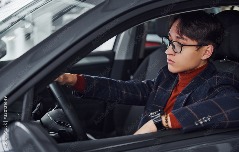 Man in eyewear and formal clothes sitting inside of modern car