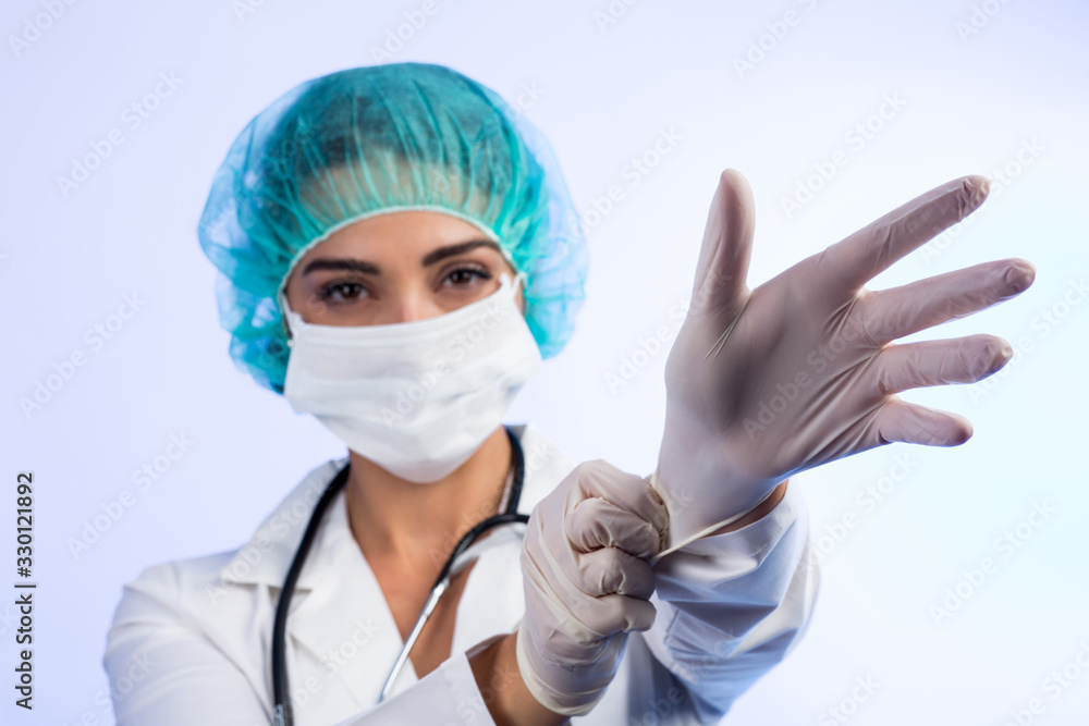 Medico con cuffia, mascherina, guanti si prepara ad operare , isolata su sfondo chiaro Medico con cuffia, mascherina, guanti si prepara ad operare , isolata su sfondo chiaro