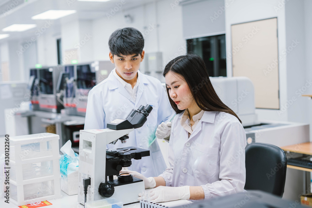 Two medical scientist working in Medical laboratory , young female scientist looking at microscope Two medical scientist working in Medical laboratory , young female scientist looking at microscope