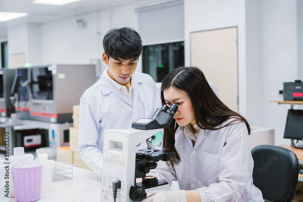 Two medical scientist working in Medical laboratory , young female scientist looking at microscope Two medical scientist working in Medical laboratory , young female scientist looking at microscope