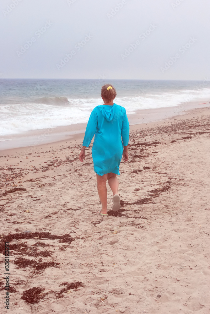 Mature female walking on the beach in the sand.