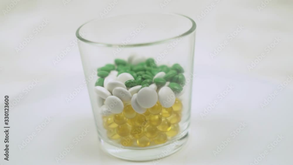 Green Tablets Fall into a Glass Cup to the Tablets and Vitamins. Medicines and Pharmaceuticals. Concept of Health and Medicine. Green Tablets Fall into a Glass Cup to the Tablets and Vitamins. Medicines and Pharmaceuticals. Concept of Health and Medicine.