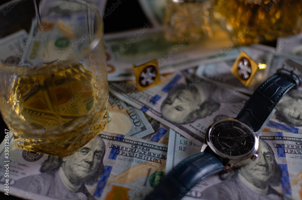 Whiskey, watch, dollars and cufflinks for a shirt on a table