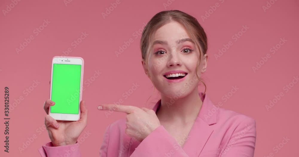Extremely Happy, Satisfied Girl showing Green Screen on Smartphone. Natural Beautiful Girl posing on Studio in stylish Outfit, showing Green Screen to the Camera. Girl likes New Mobile App. Phones. Extremely Happy, Satisfied Girl showing Green Screen on Smartphone. Natural Beautiful Girl posing on Studio in stylish Outfit, showing Green Screen to the Camera. Girl likes New Mobile App. Phones.
