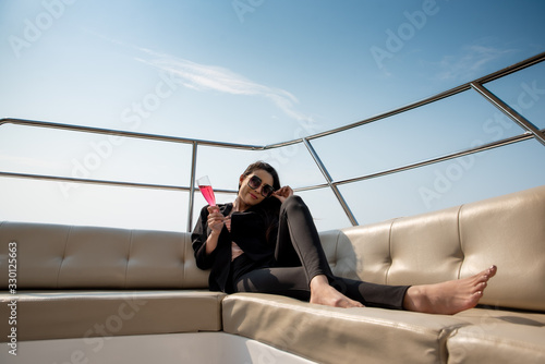 Luxury asian woman in black suit drinking champagne on the yacht.