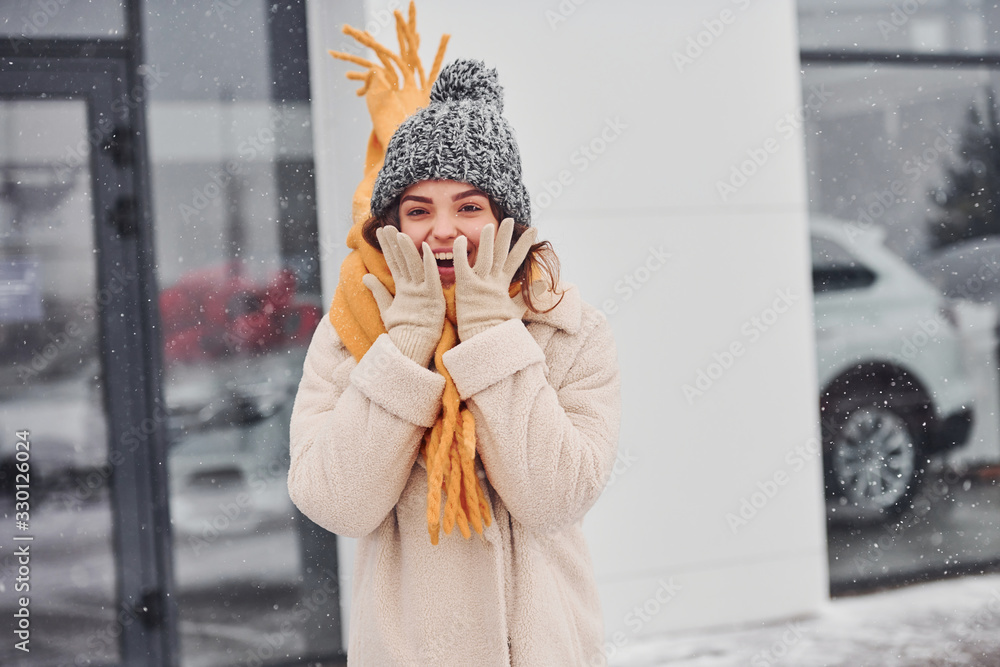 Fototapeta premium Cheerful young girl smiling standing and smiling outdoors. Snow is falling