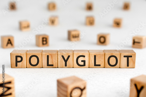 Polyglot - word from wooden blocks with letters, knowing or using several languages polyglot concept, random letters around white background