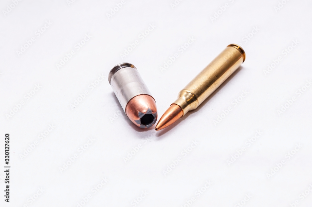 Two bullets, a 45 auto hollow point and a 223 caliber rifle bullet on a white background Two bullets, a 45 auto hollow point and a 223 caliber rifle bullet on a white background