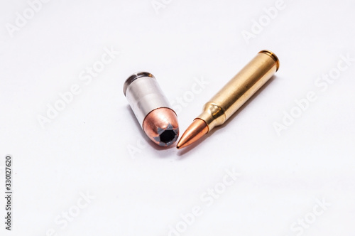 Two bullets, a 45 auto hollow point and a 223 caliber rifle bullet on a white background