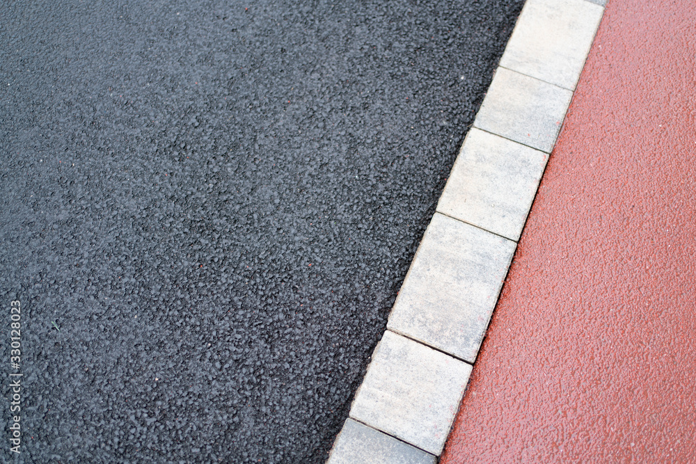 Two types of asphalt separated by a brick strip red and black, soft and hard. Pedestrian asphalt and asphalt for cars