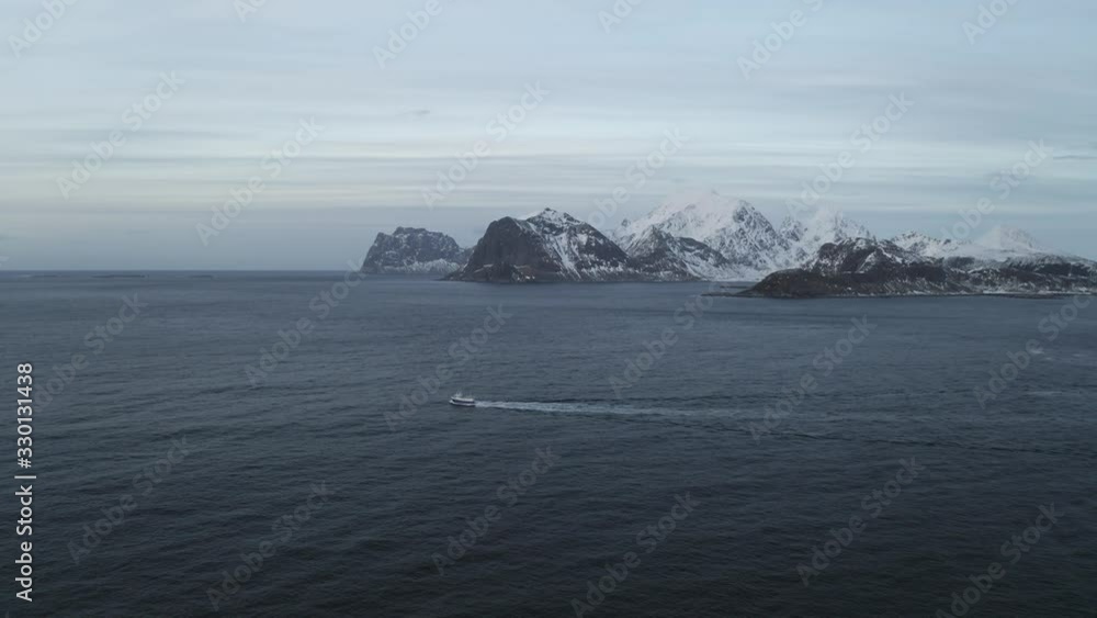 Fishing boat sailing to the ocean in arctic area of Lofoten Islands located north of norway during winter.Winter is main fishing season and cod fish is very famous from Norway.Mountains in background Fishing boat sailing to the ocean in arctic area of Lofoten Islands located north of norway during winter.Winter is main fishing season and cod fish is very famous from Norway.Mountains in background