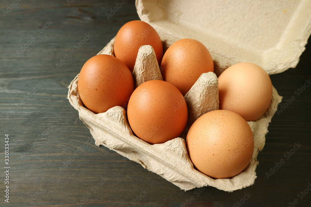 Organic Chicken Eggs in Paper Carton Box Isolated on Dark Brown Wooden Table Organic Chicken Eggs in Paper Carton Box Isolated on Dark Brown Wooden Table