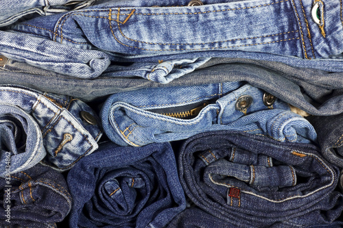 Pile of jeans clothes of various colors as a background