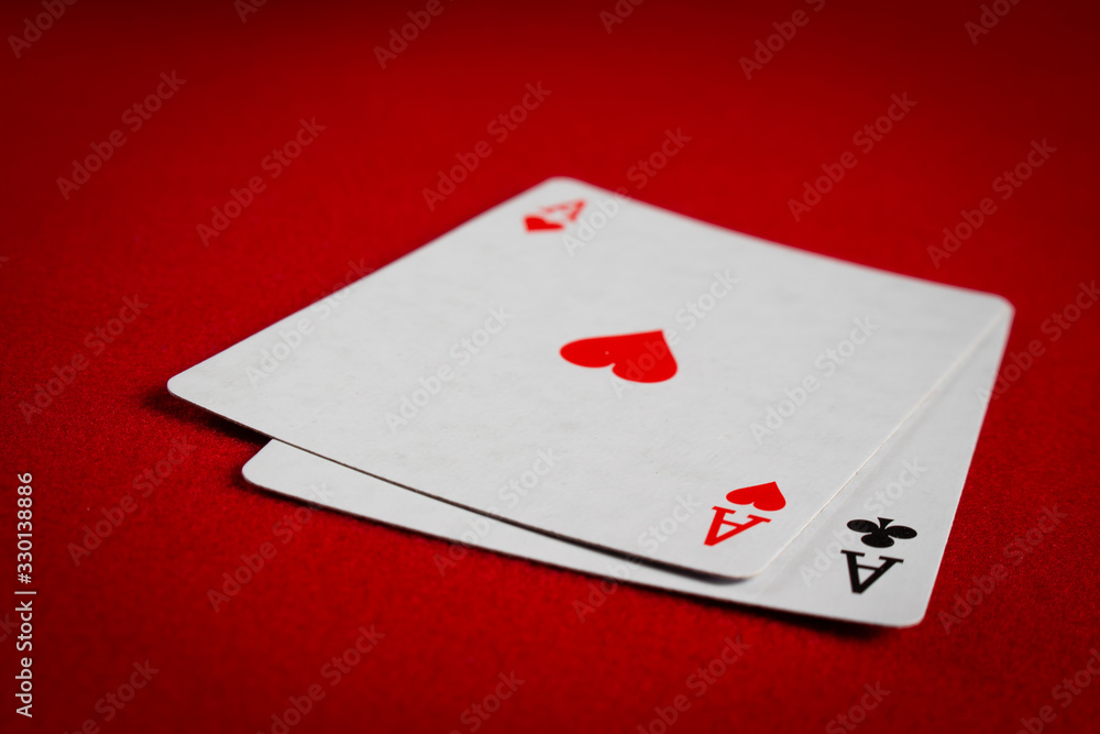 A pair of aces on a red poker table