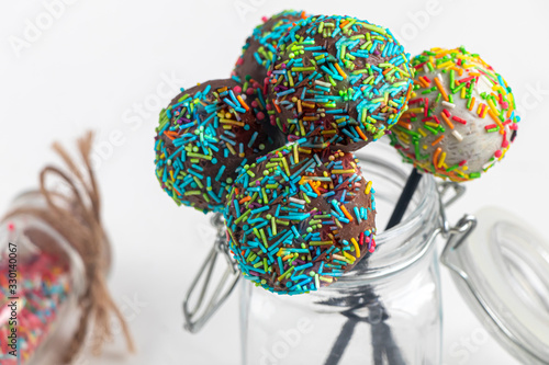 A colorful cake pops up, lying on a table. It is covered with sweet multi-colored sweets.