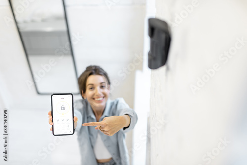 Foto Woman controlling alarm system with a smart phone, showing phone with launched mobile application