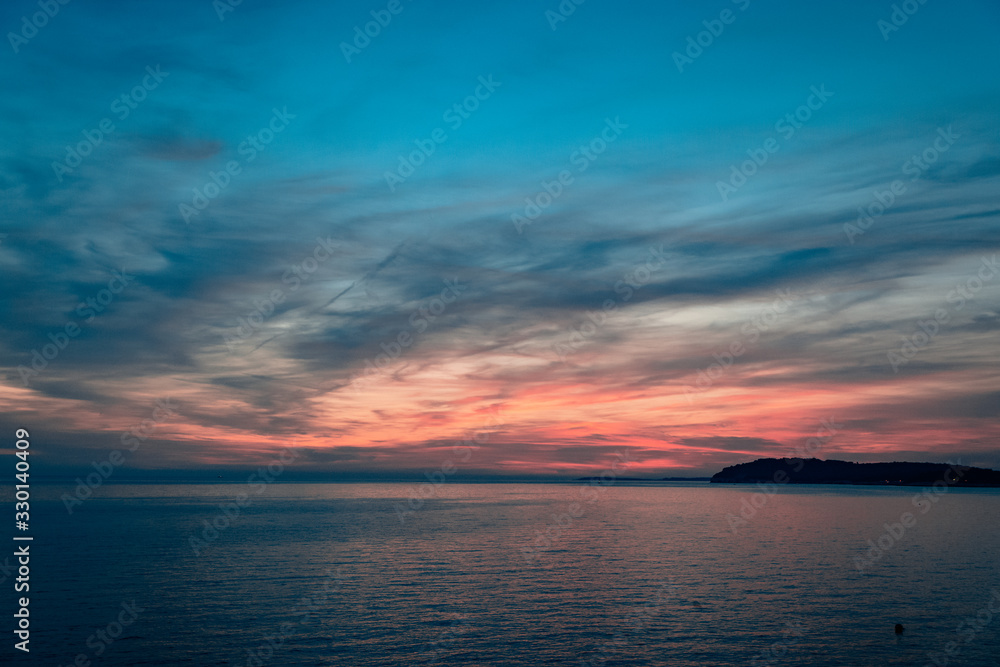 Sunset over the sea, colorful clouds, wide shot. Romantic picture full of colors.