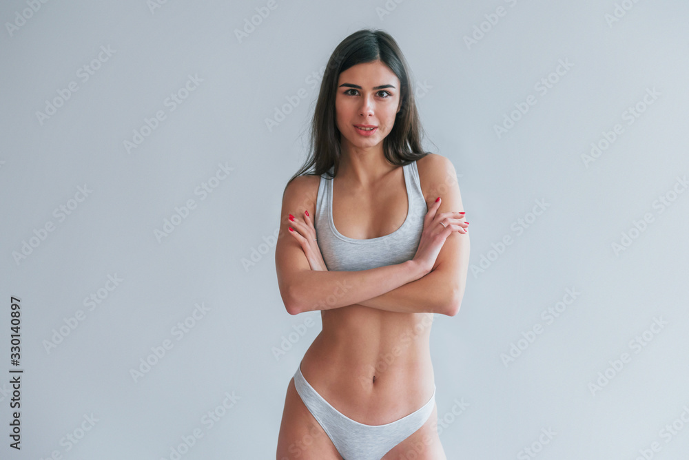 Fototapeta premium Young beautiful brunette in underwear is indoors in the studio against white background