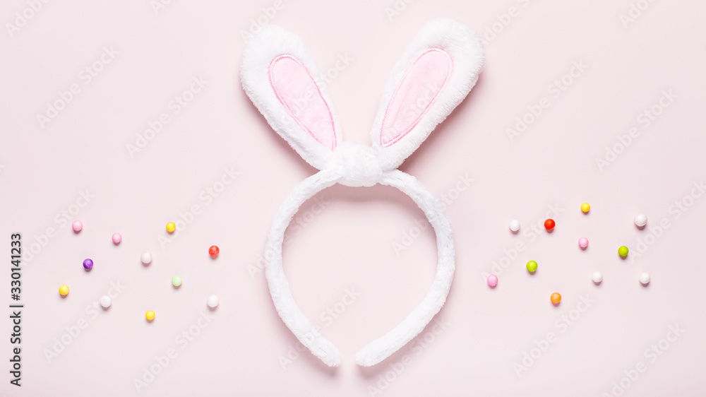 Funny cute bunny eggs and bunny rabbit ears for kids on pastel pink table top, Easter holiday concept. Easter decoration for kids flat lay, copy space