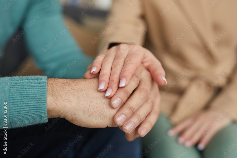 Close-up of woman supporting the man and holding his hand while they sitting on the sofa