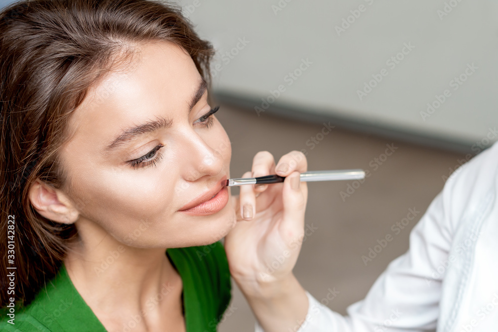 Makeup artist applies lipstick. Makeup artist applies lipstick.