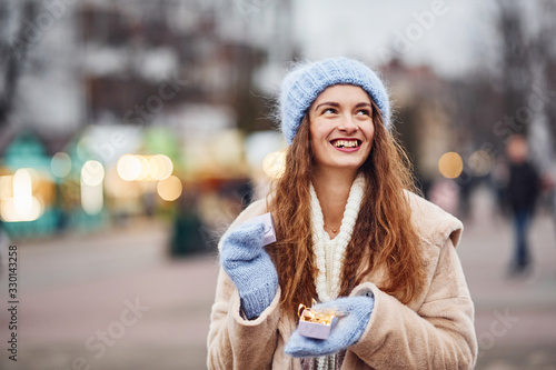 Young positive girl holds little gift box in hands outdoors in the city © standret