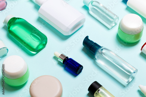 Top view of cosmetic products in different jars and bottles on blue background. Close-up of containers with copy space