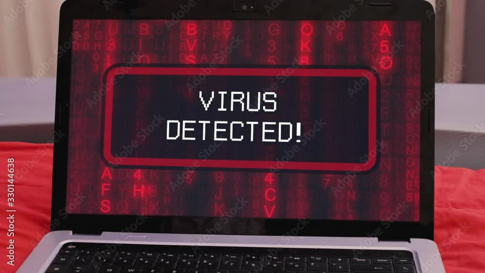 A laptop showing the text Virus detected, appearing on a board over random symbols falling down (a popular sci-fi movie fx), changing their color from green to red. A laptop showing the text Virus detected, appearing on a board over random symbols falling down (a popular sci-fi movie fx), changing their color from green to red.