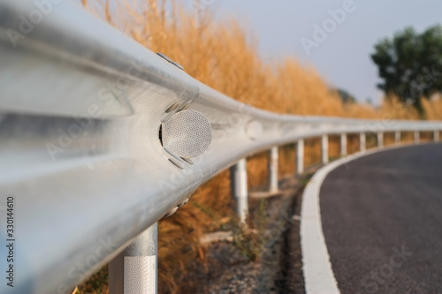 White reflective sign warn curve at night on the steel guard rail on the road in day time.