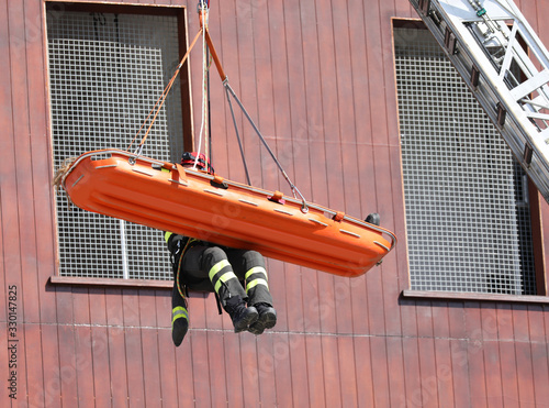 suspended firefighter with stretcher with people during practice