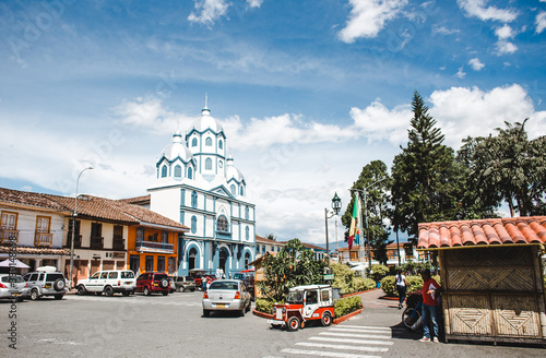 Colourful traditional houses and a blue & white Catholic church on the main plaza of Filandia, a typical Colombian town in the Quindio coffee region photo