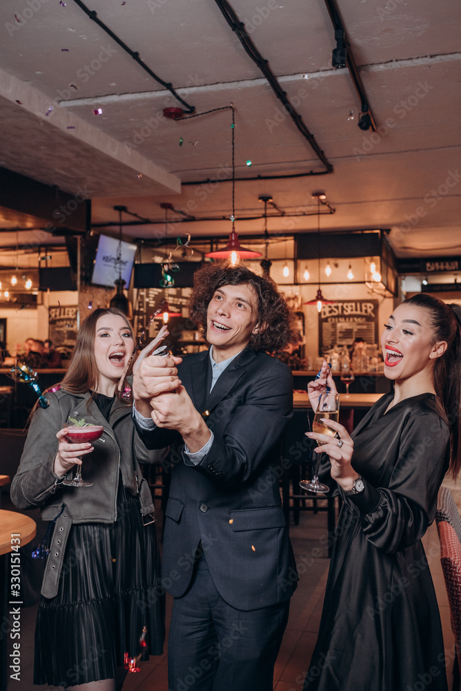 two young girls in black dresses and a curly haired guy have fun in a restaurant