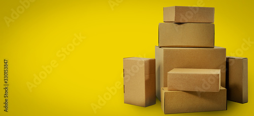 shipping and delivery - blank cardboard boxes on yellow background with copy space © ronstik