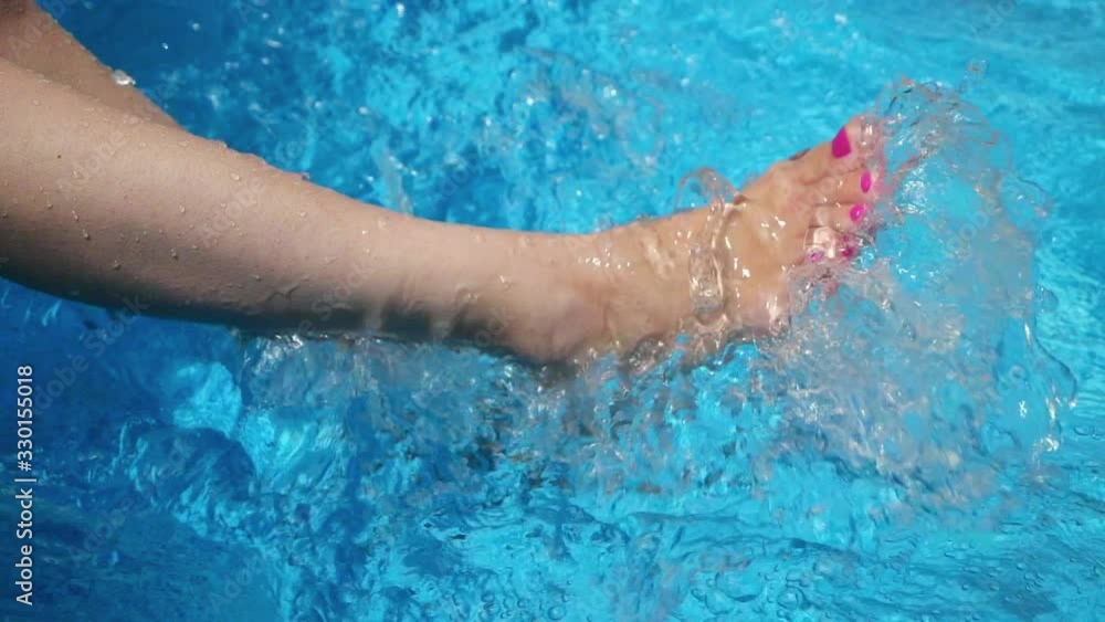 Woman sitting on the edge of a pool dangling feet in the water. Woman sitting on the edge of a pool dangling feet in the water.