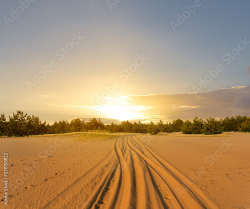 dramatic sunset over the sandy desert with road far away