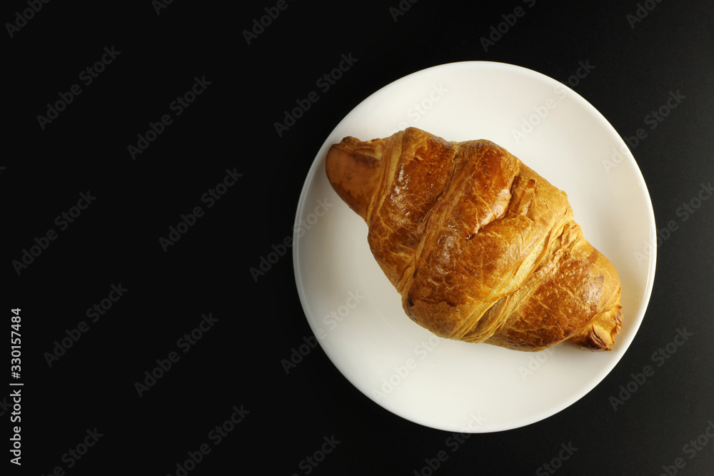 croissant in a white plate on a black background