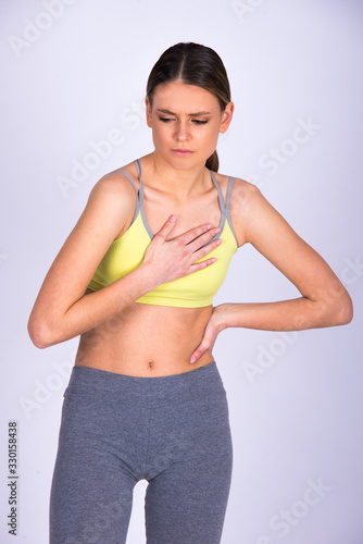 Young woman feeling chest pain while exercise, isolated on white. Fitness Caucasian girl © oreans