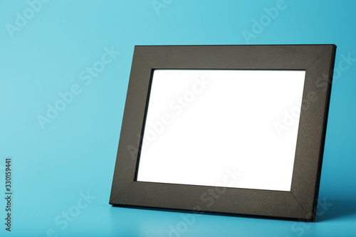 Black photo frame with empty space on a blue background.