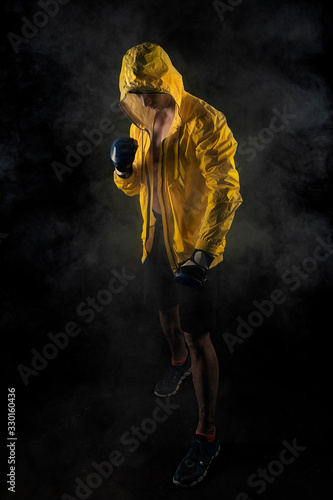 hombre musculoso con guantes de boxeo y anorak amarillo en fondo negro