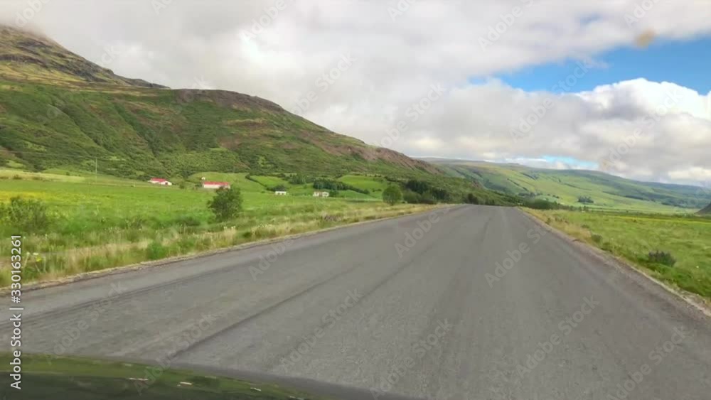 Car driving on the road in Iceland. View of the road from inside of the car. Beautiful  nature of Iceland, wide spaces, mountains, blue sky with clouds