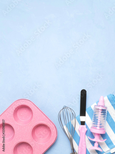 Cake pan, spatula, whisk, towel on a blue concrete background. A copy of the space.