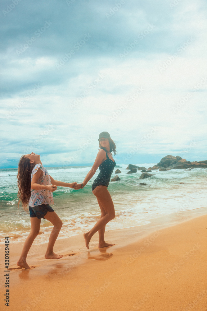 family relationship, mother with daughter are walking on the beach and laughing. vacation concept, free space
