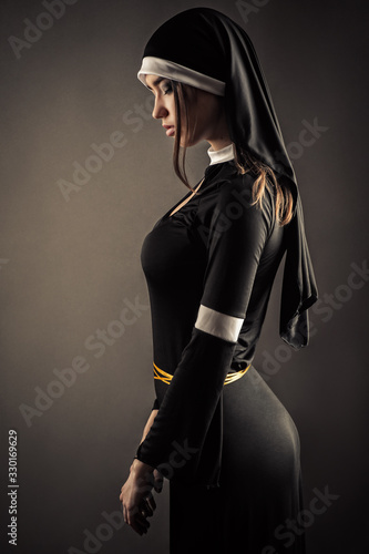 young nun in a black robe standing with closed eyes